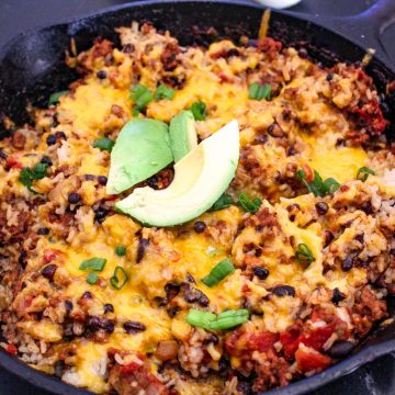 Mexican skillet supper in cast iron skillet garnished with green onion and avocado