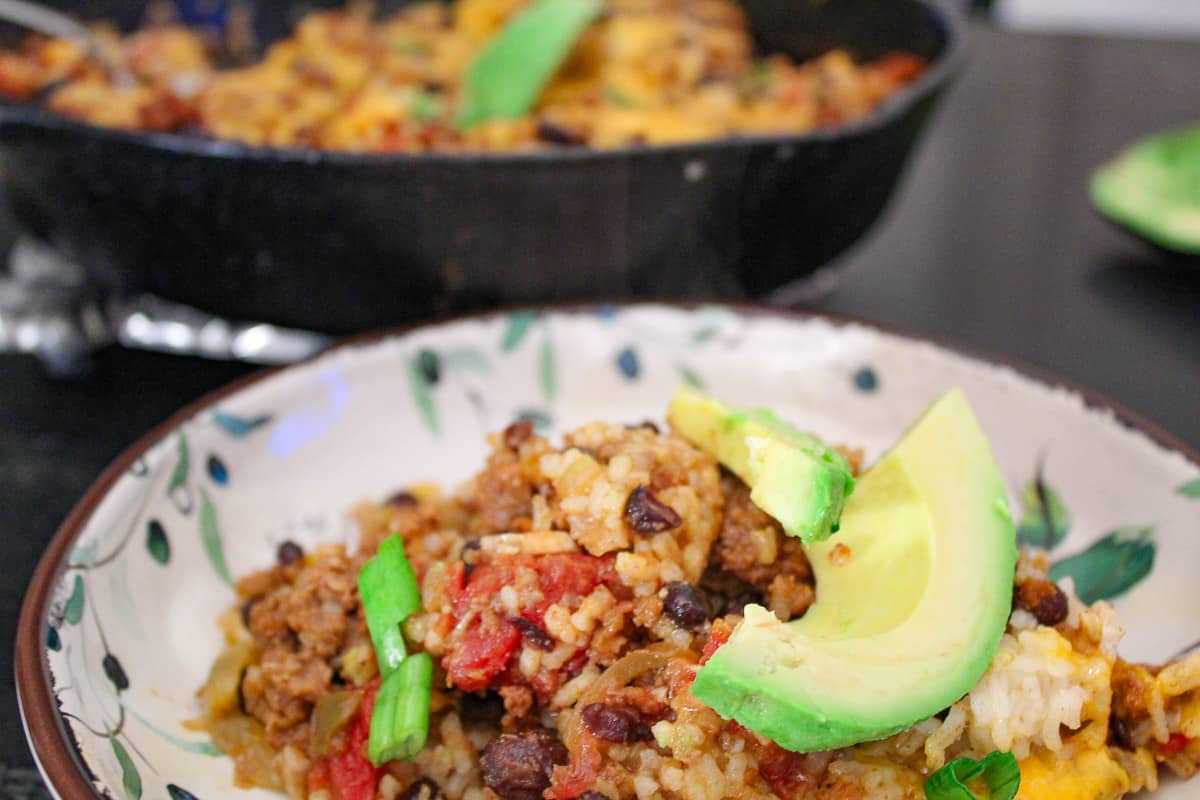 Mexican Skillet Supper in decorative bowl garnished with sliced avocado