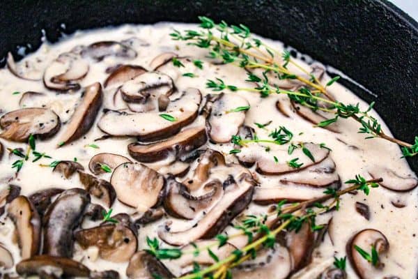 Mushroom Cream Sauce garnished with sprigs of thyme in a black skillet