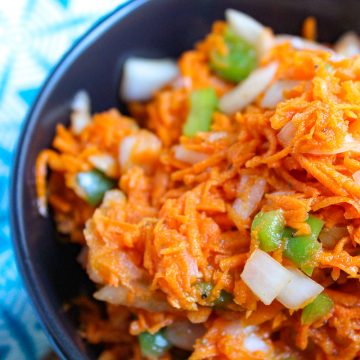 Carrot Slaw in black bowl with bell peppers and onion