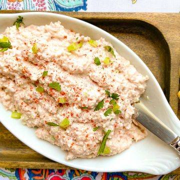 Deviled ham spread in a white oval bowl with a spreader and a side of crackers