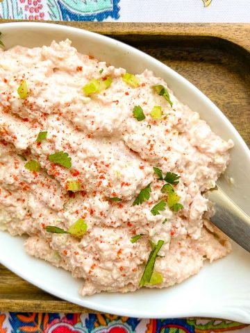 Deviled ham spread in a white oval bowl with a spreader and a side of crackers