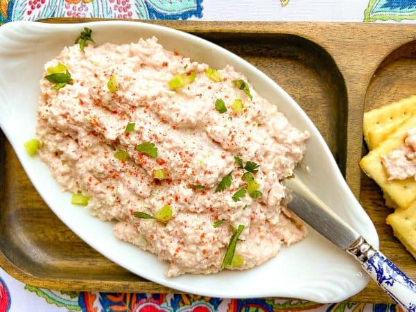 Deviled ham spread in a white oval bowl with a spreader and a side of crackers