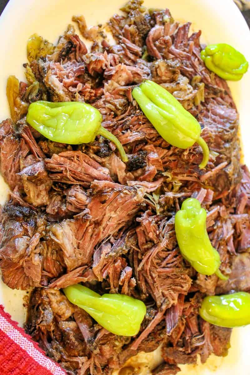 Shredded Mississippi Pot roast with Pepperoncini peppers on white plate