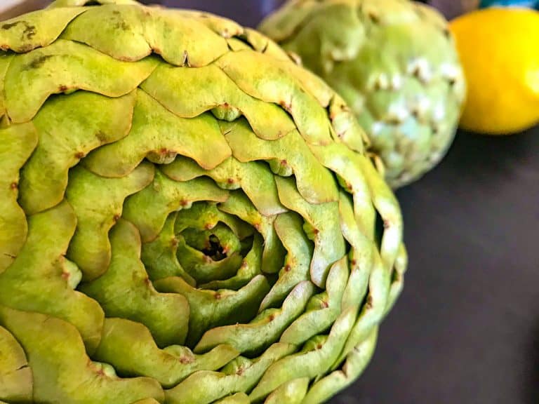 Whole artichoke on black counter