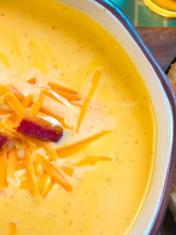 Cheese soup garnished with bacon and shredded cheddar