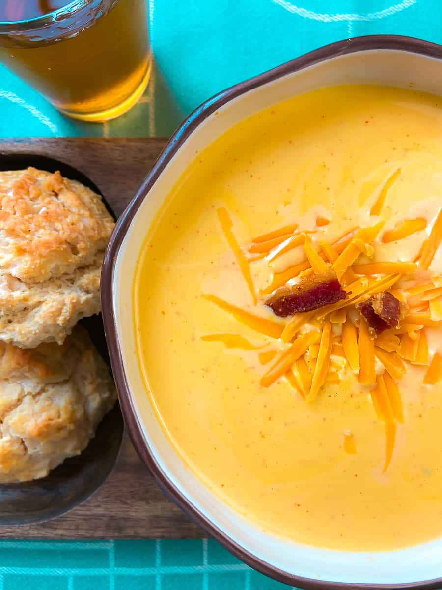 Soup in a bowl with a side of amber beer and biscuits.