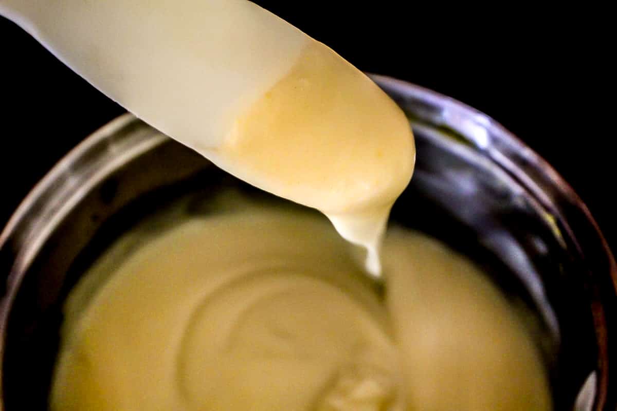 Condensed soup on spatula over saucepan.