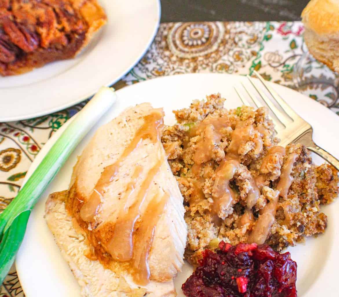 Cornbread dressing, turkey and cranberry sauce on white plate