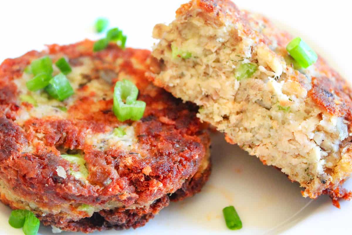 Two salmon croquettes with one cut in half on white plate