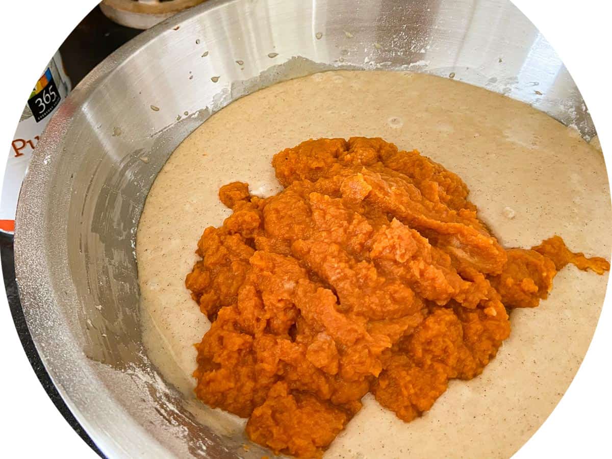 Pureed canned pumpkin being added to mixture
