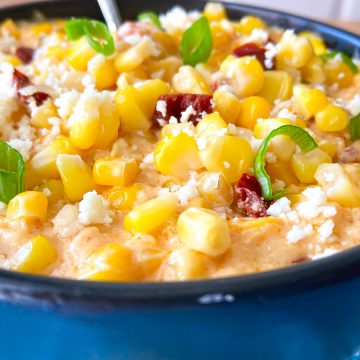 Corn Casserole in black dish garnished with green onion and crumbling cheese