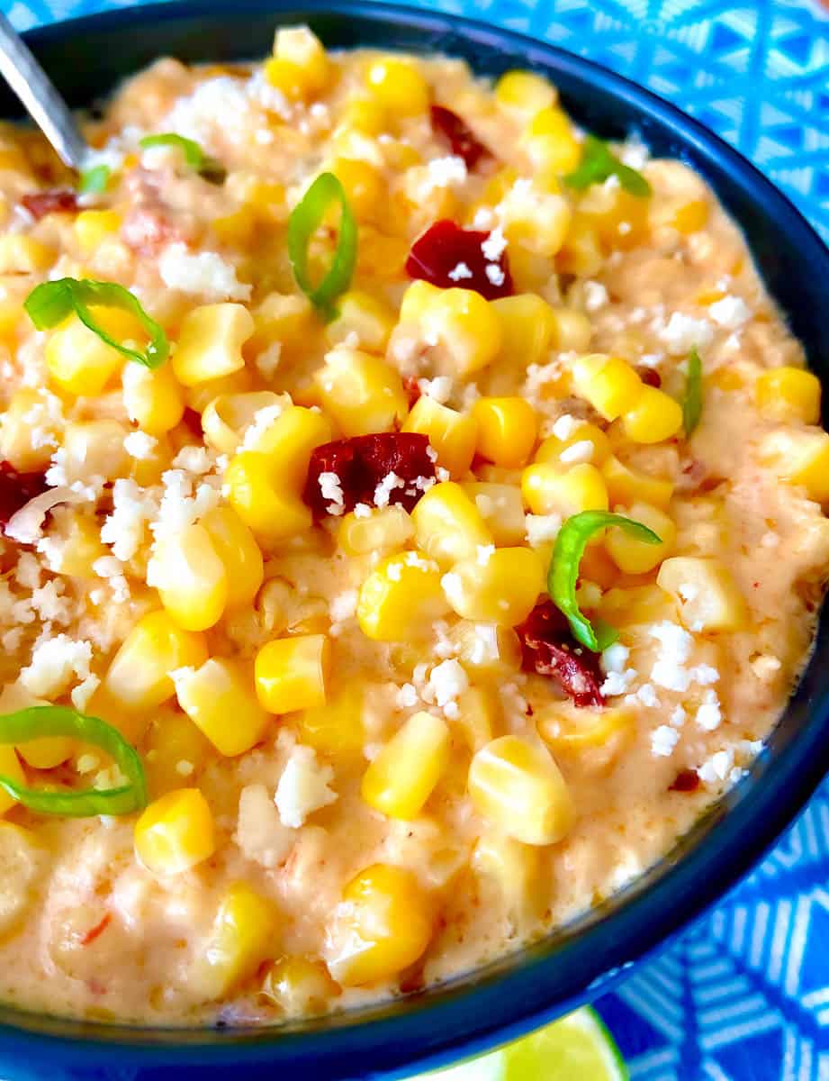 Sweet Chipotle Corn Casserole in black bowl garnished with green onion and cheese.