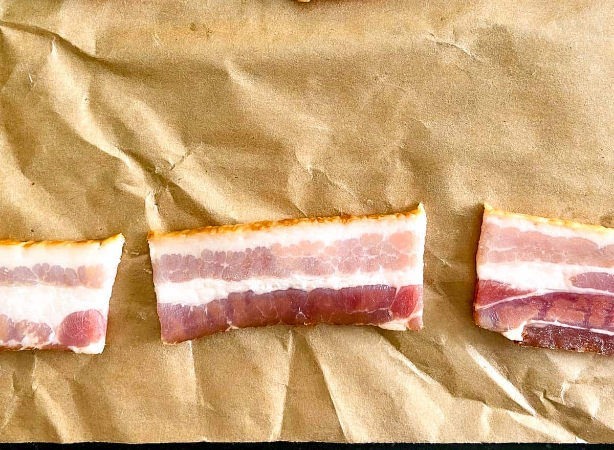 A strip of bacon cut into thirds on brown butcher paper