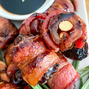 Almond stuffed dates stacked on plate with side of balsamic glaze