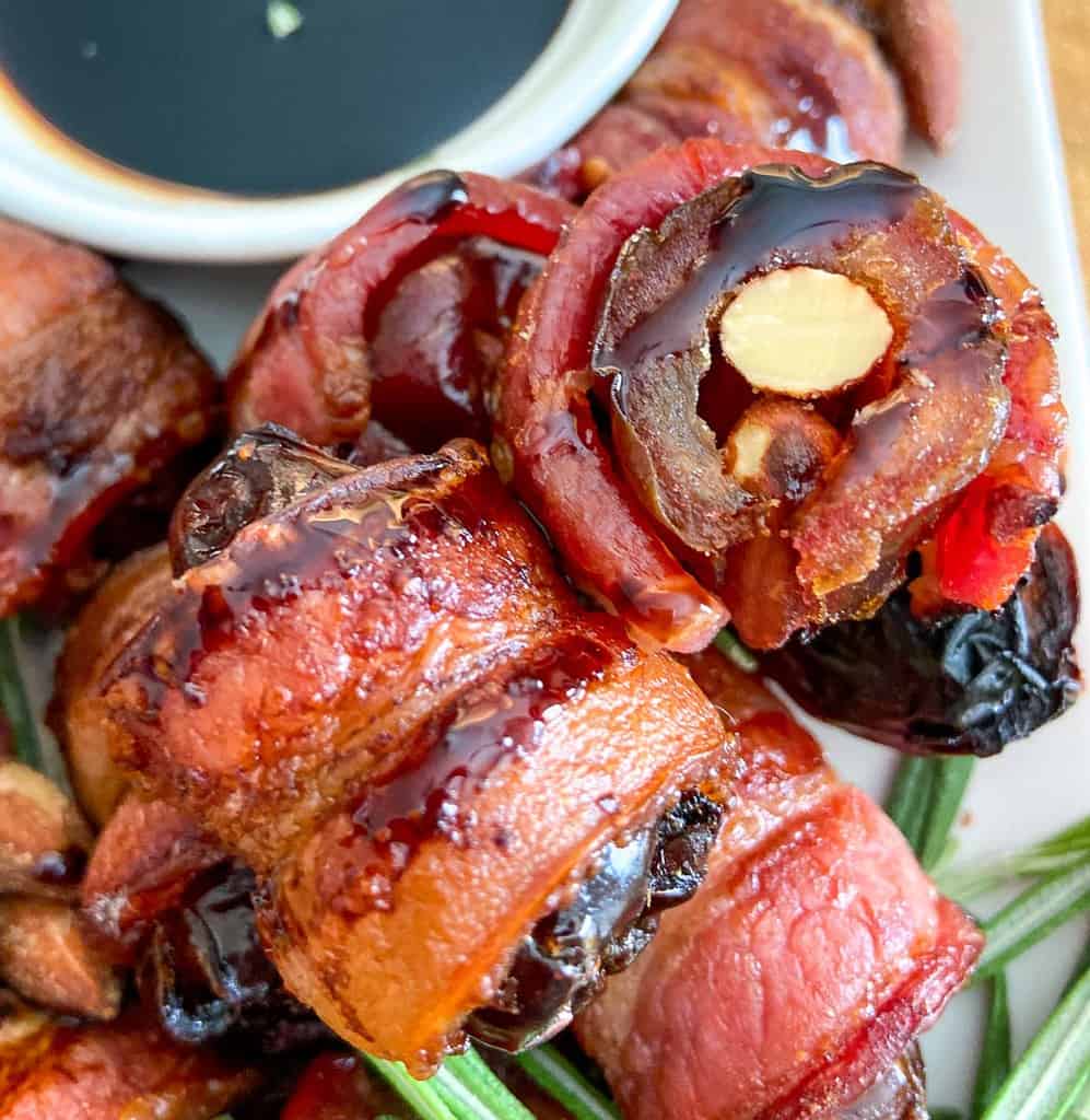 Almond stuffed dates stacked on plate with side of balsamic glaze