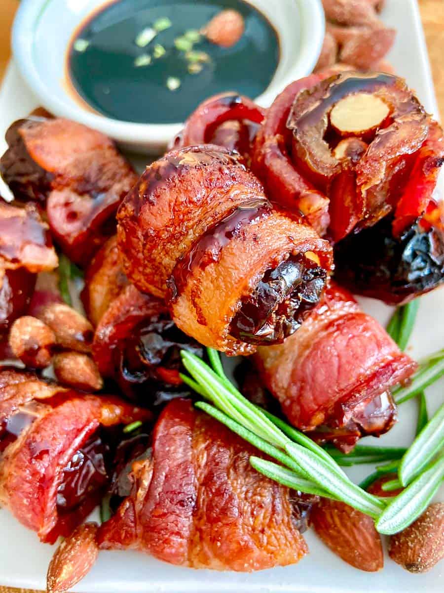 Hickory Almond Stuffed Dates stacked on white plate and garnished with fresh rosemary sprigs.