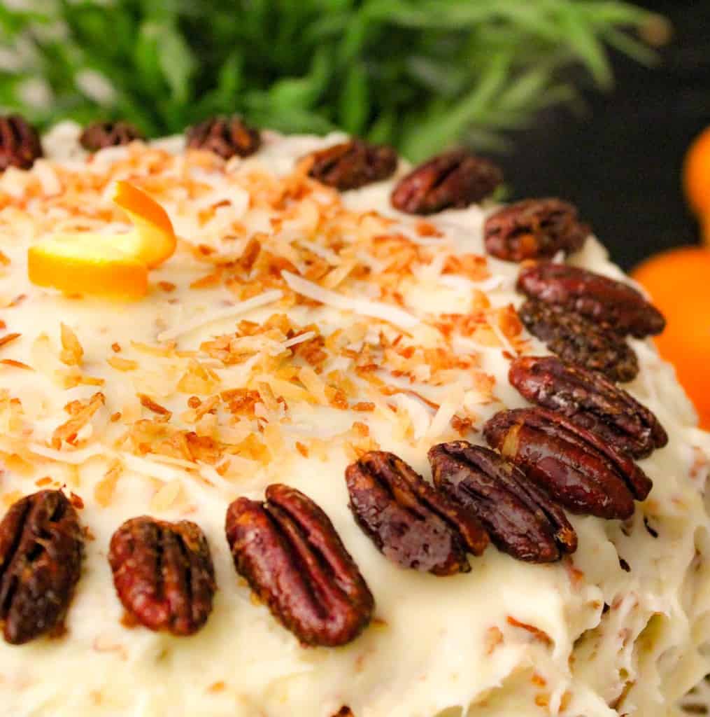 Orange Italian Cream Cake on cake plate with oranges in the background