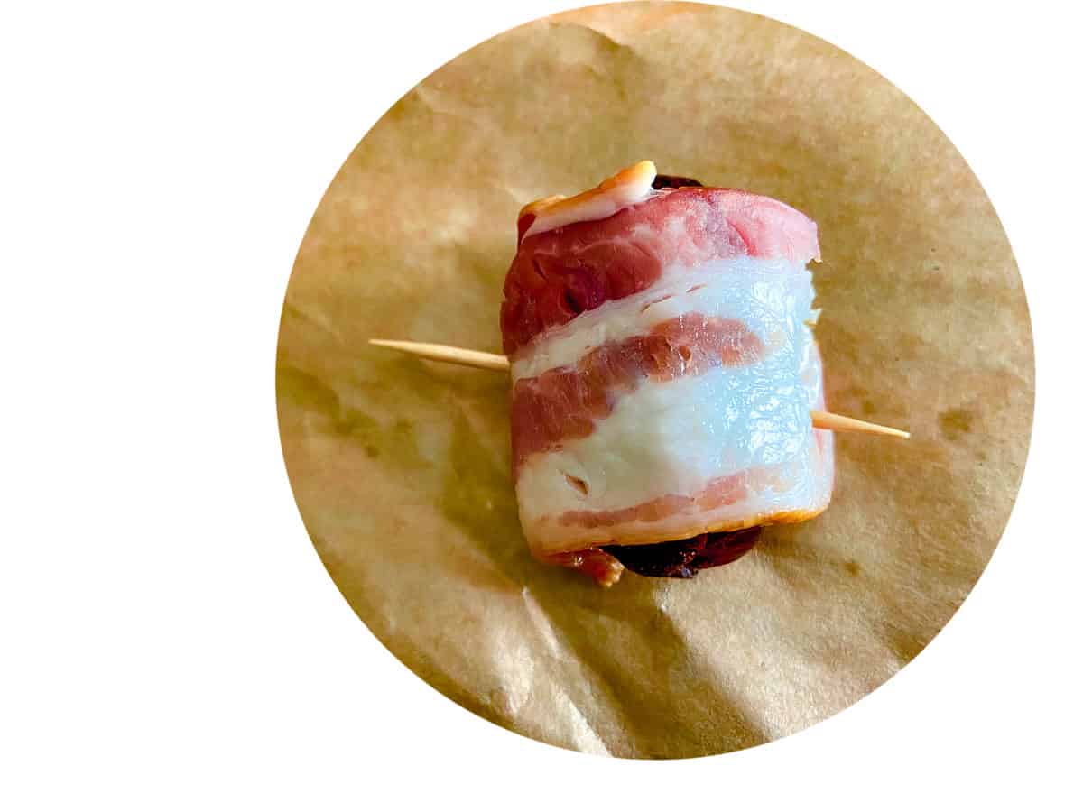 Bacon wrapped around stuffed date with toothpick in it