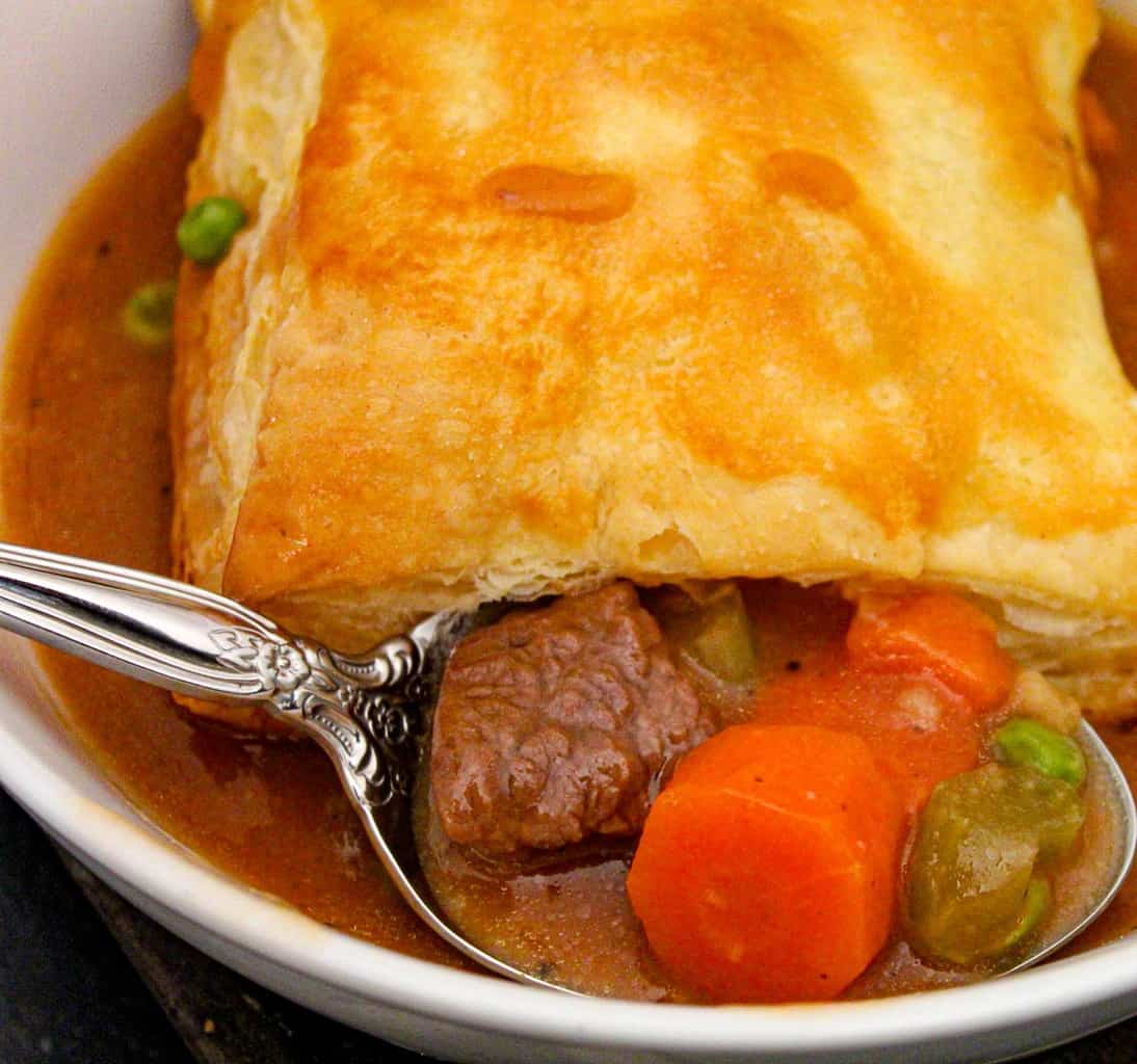 A spoonful of beef stew in a white bowl