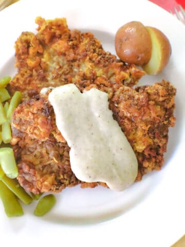 Chicken fried steak with cream gravy and a side of green beans