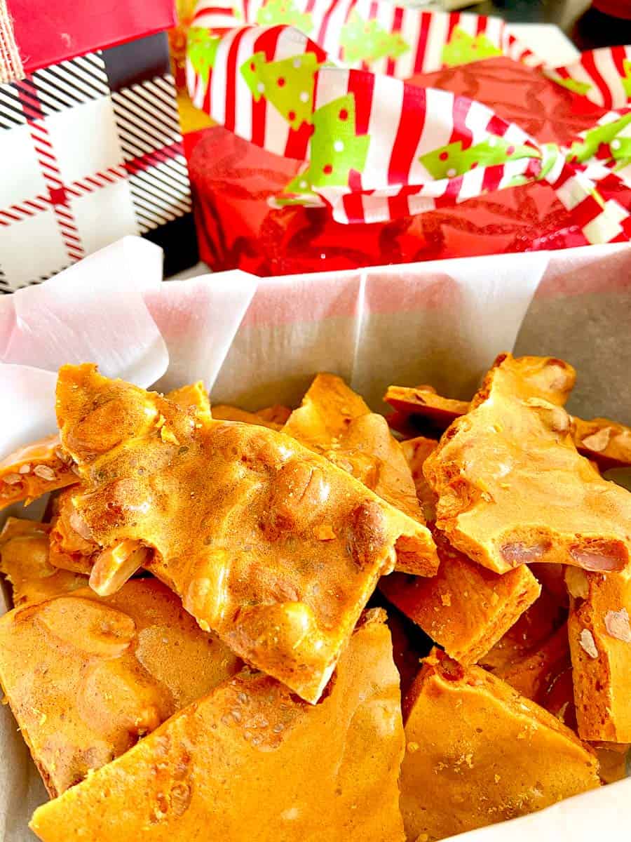 Cracked peanut brittle in a gift box with white tissue paper.