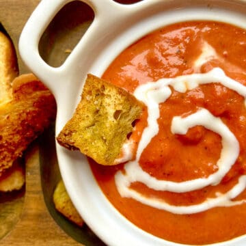 Smoked tomato bisque on brown serving tray with crouton and cream