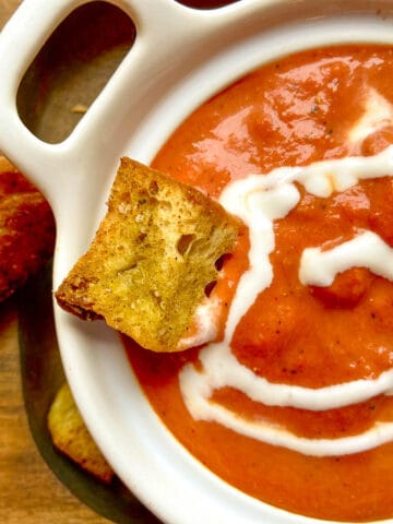 Smoked tomato bisque on brown serving tray with crouton and cream