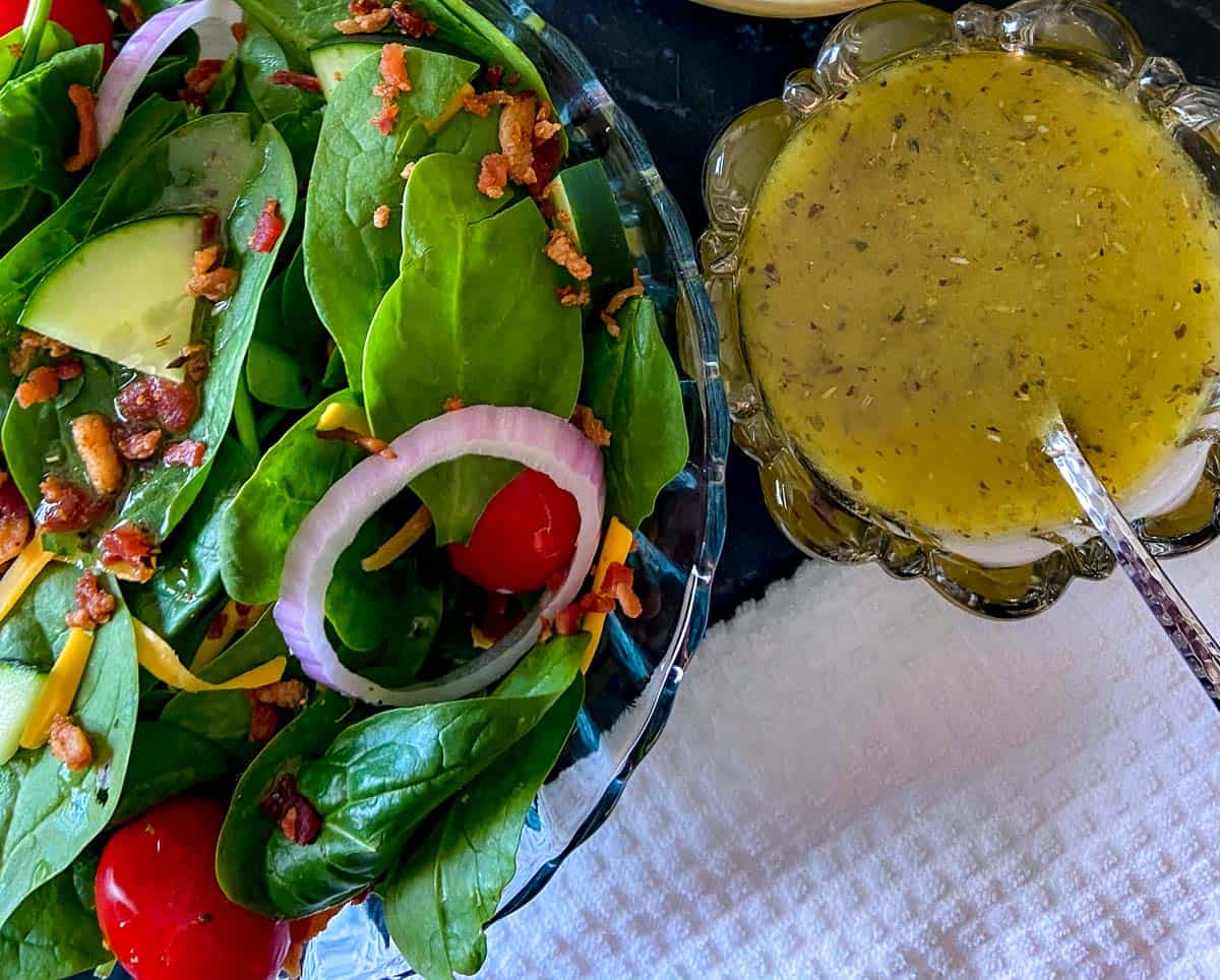 Spinach salad in a glass bowl with a side of White balsamic vinaigrette