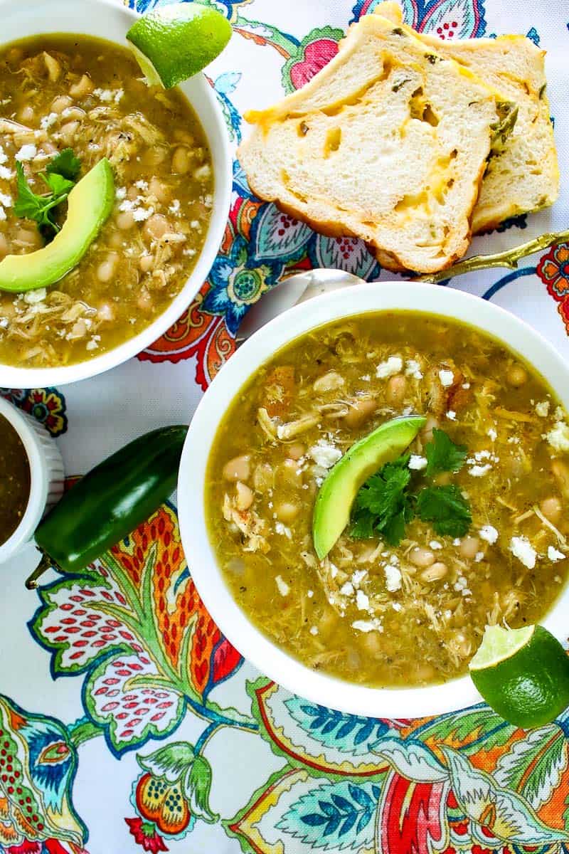 White bowl of green chicken chile on floral tablecloth