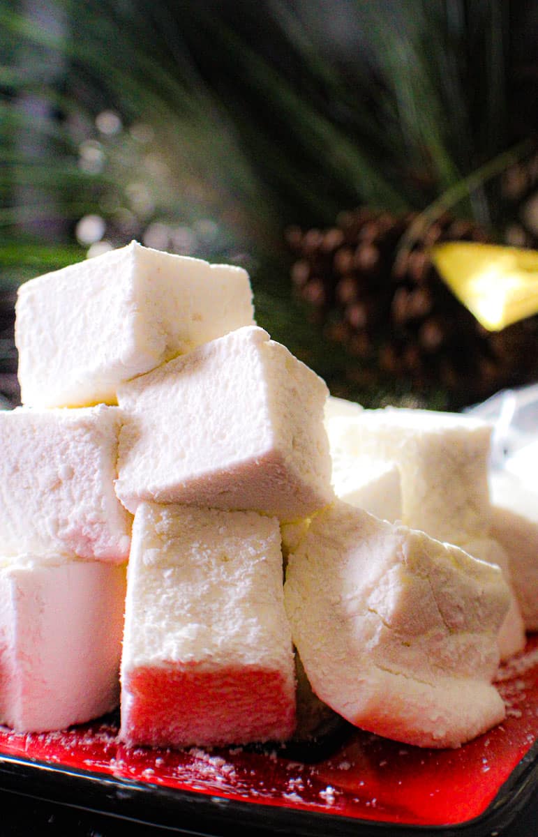 Homemade marshmallow squares stacked on a red plate