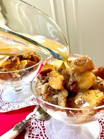 Whiskey sauce drizzled over bread pudding in fluted glass bowl