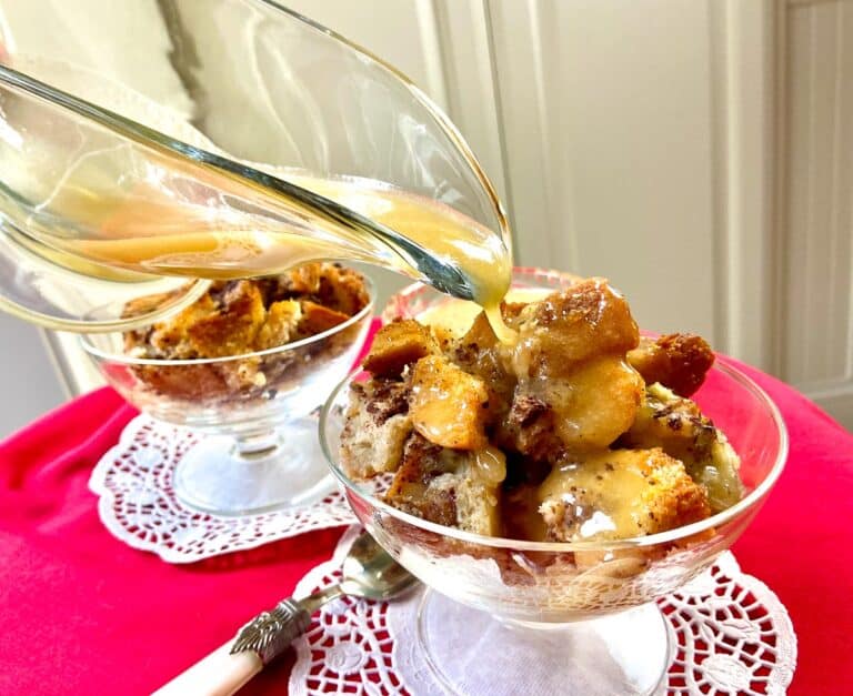 Whiskey sauce drizzled over bread pudding in fluted glass bowl