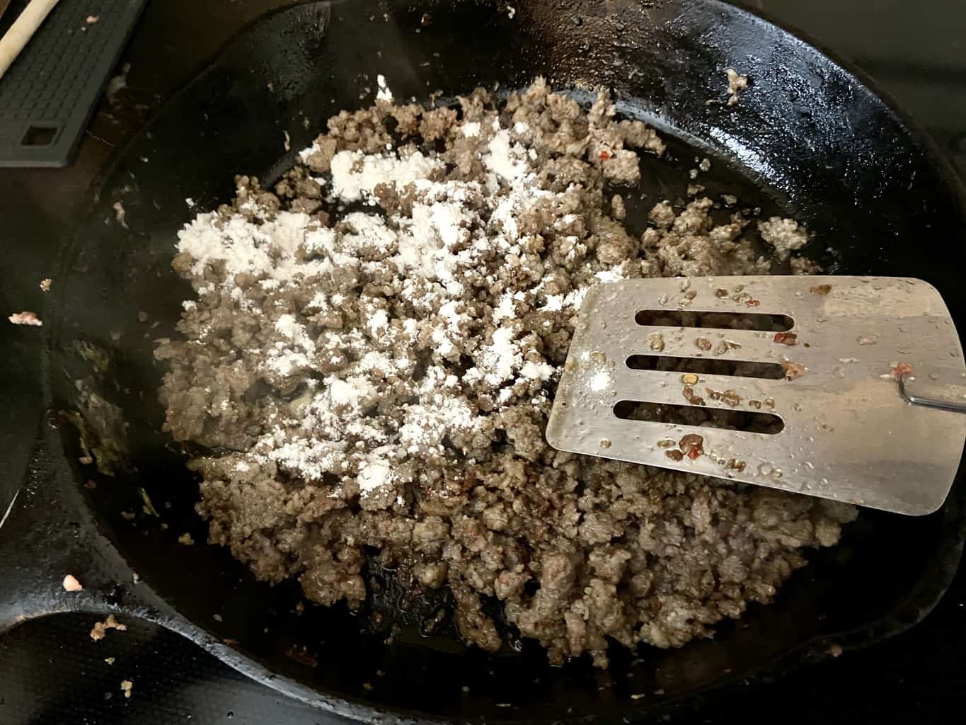 Add flour in increments to cooked sausage