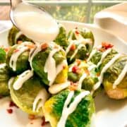 Horseradish Cream Sauce being spoon drizzled over brussels sprouts