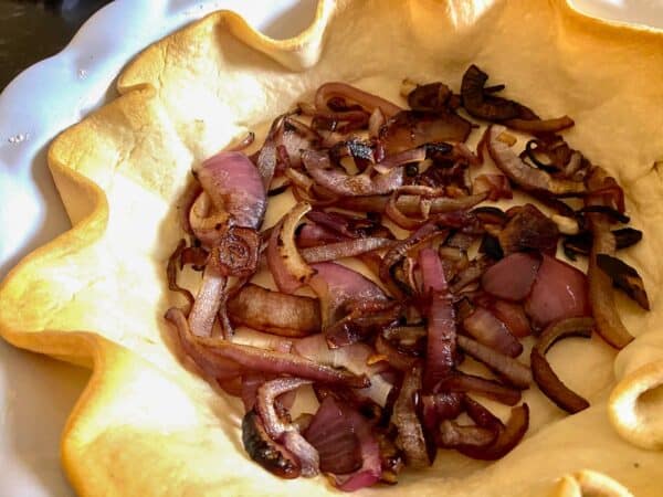 Cooked red onion in blind baked pie crust