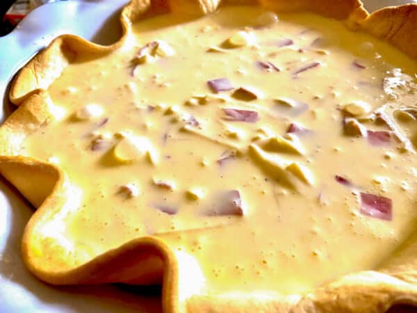 Quiche batter in baked pie crust