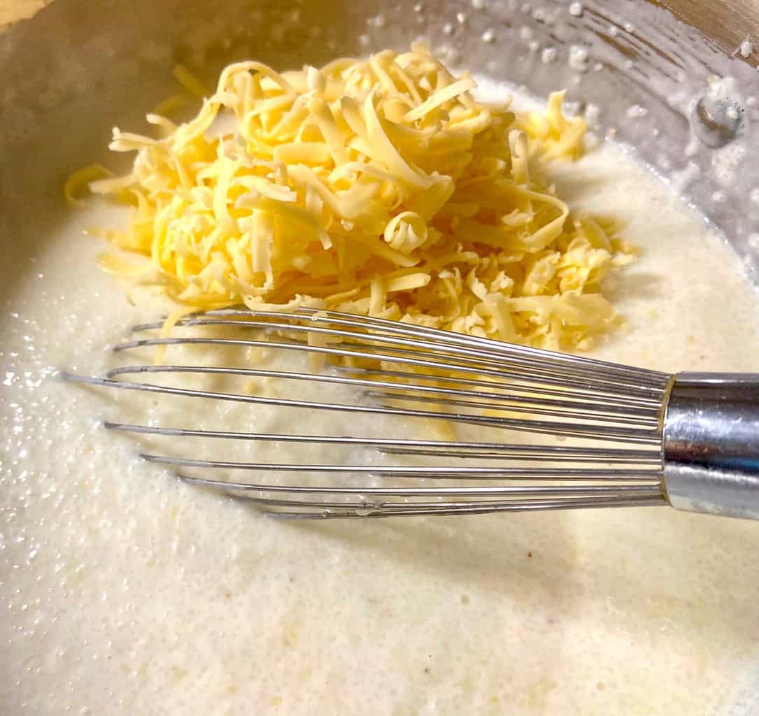 Shredded smoked gouda cheese added to grits in stockpot