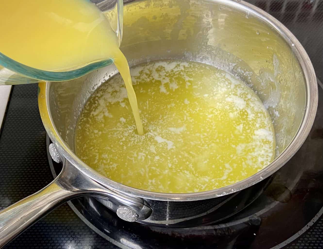 Melted butter in pan with orange juice being added