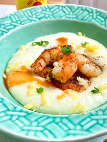 Blackened shrimp and grits in turquoise bowl garnished with parsley