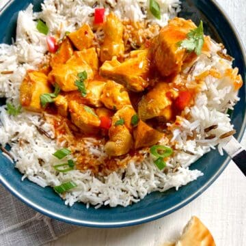 Indian Butter Chicken with basmati rice in blue bowl with serving spoon