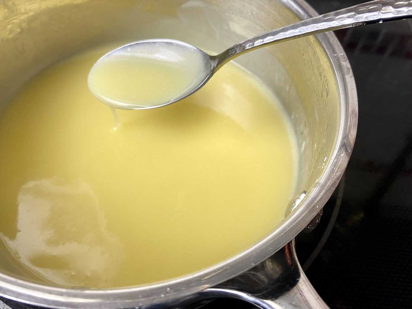 Orange sauce in pan on a spoon