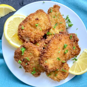 Pork Schnitzel on white plate garnished with parsley and lemon