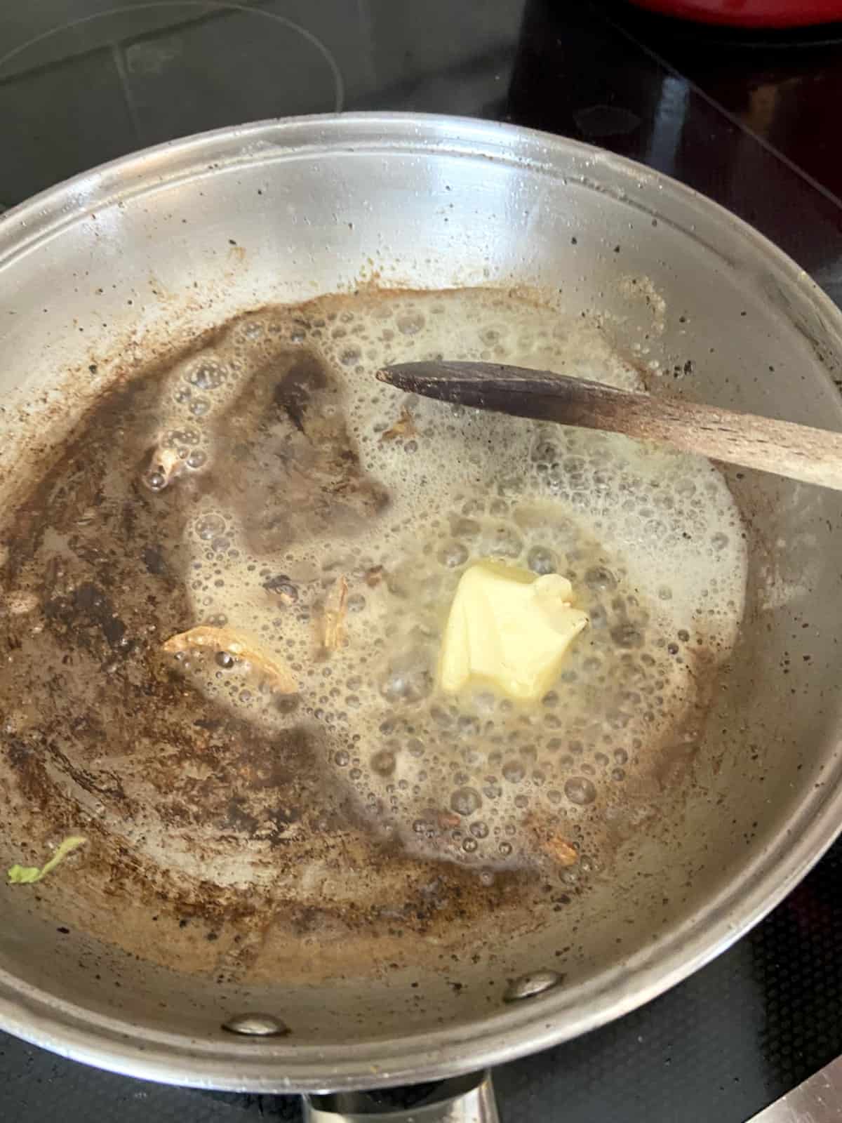 Butter being added to skillet of bacon grease.