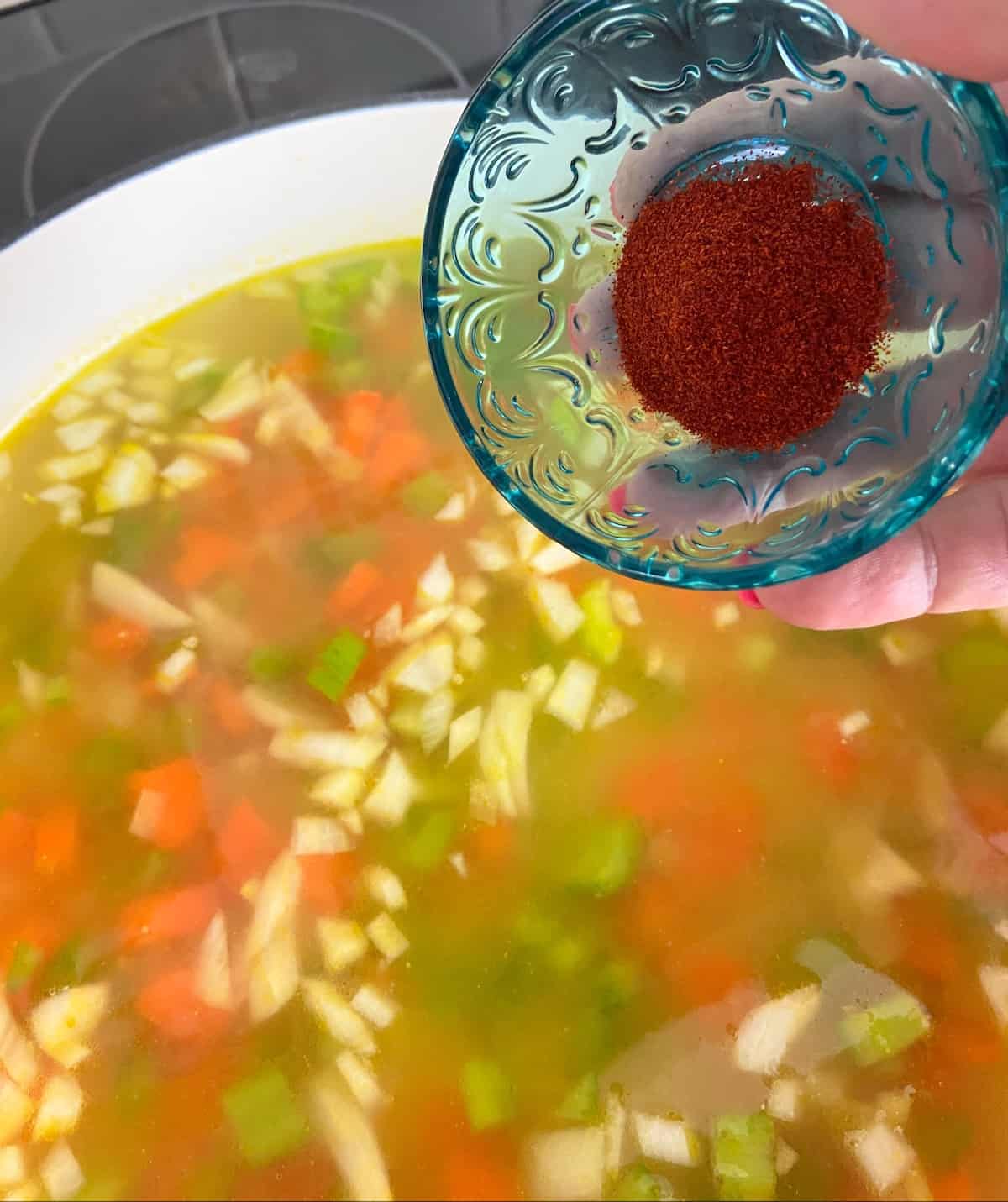 Spices being added to lentil soup broth.