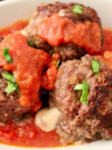 Baked Mozzarella stuffed meatballs in red sauce.