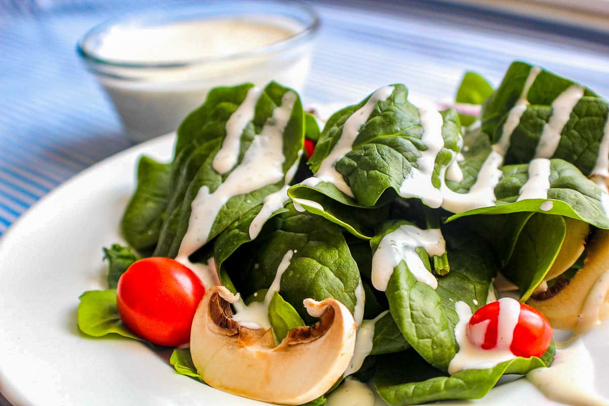 Buttermilk Dill Ranch Dressing on spinach greens with cherry tomatoes and mushroom slices.