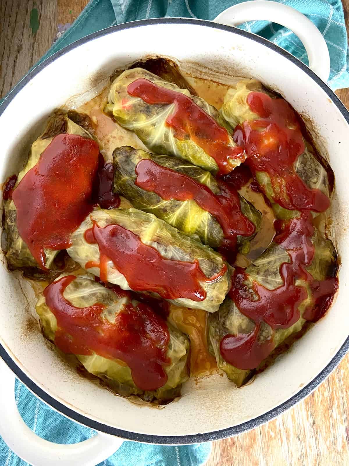 Cabbage rolls in Dutch oven topped with tomato sauce.