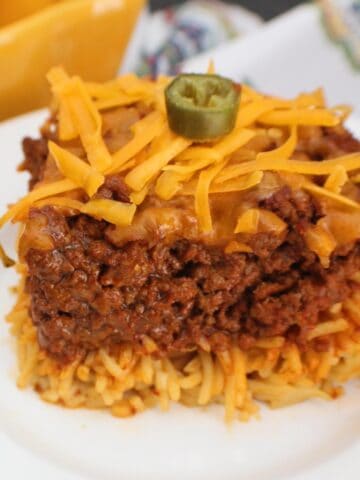Chili spaghetti pie on white plate garnished with a slice of jalapeno.