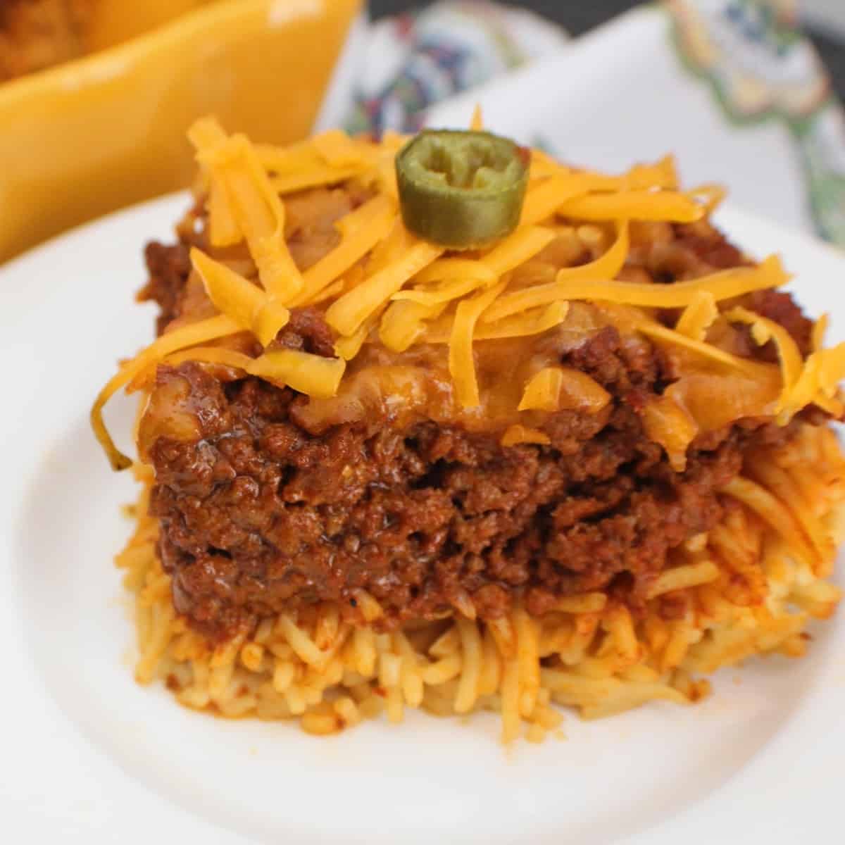 Chili spaghetti pie on white plate garnished with a slice of jalapeno.